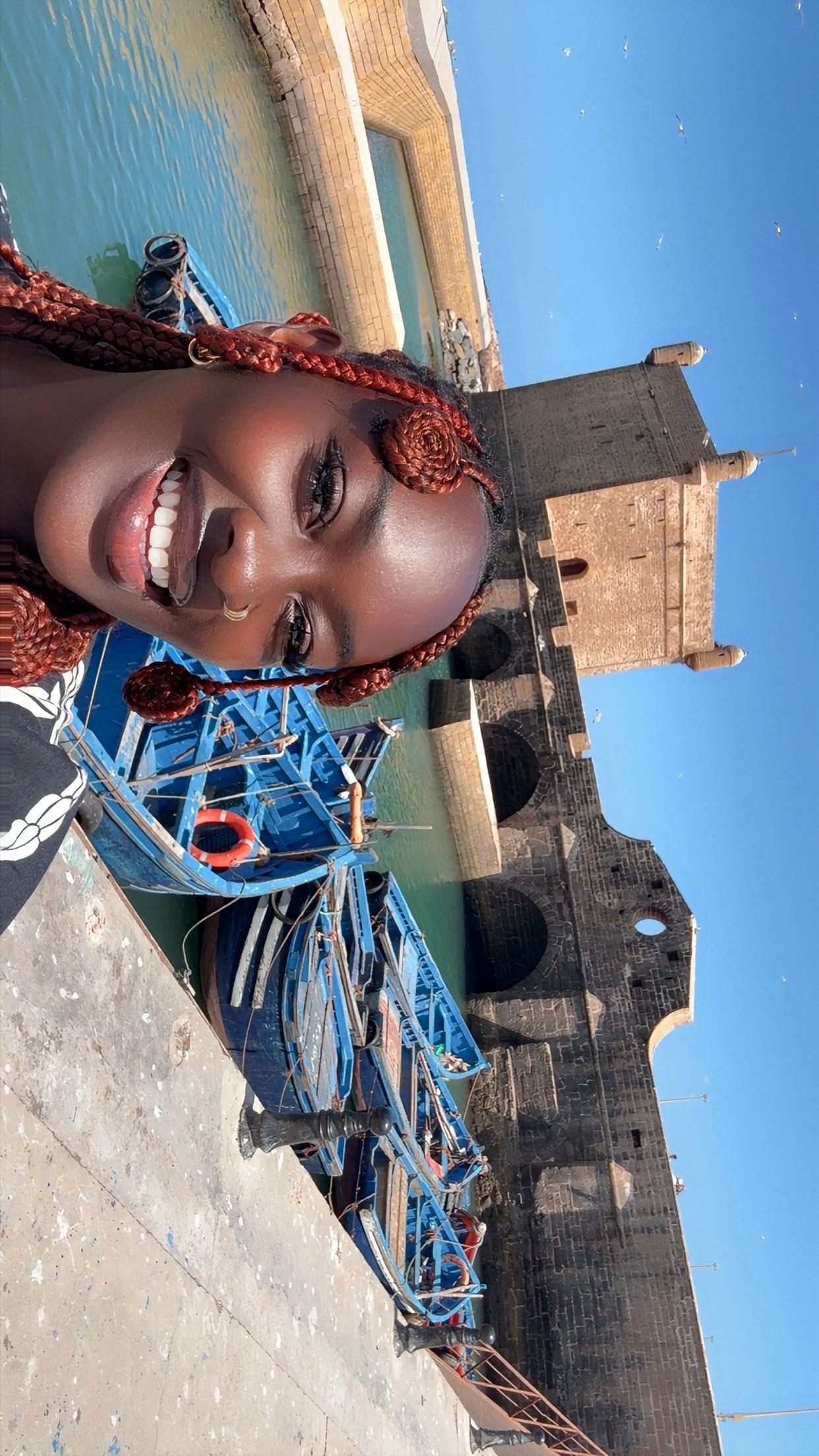 Founder smiling beside blue fishing boats in Morocco